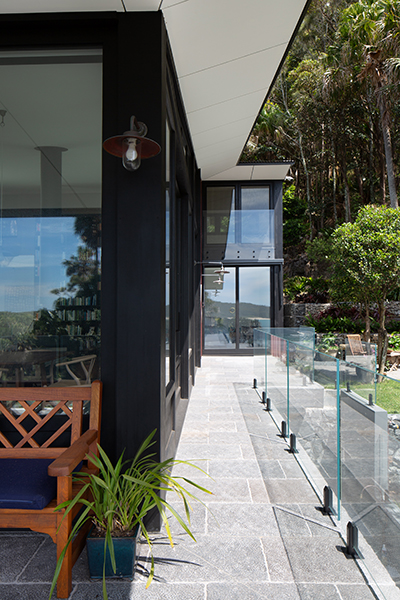 External view of the building, black bushfire safe windows and a wooden chair